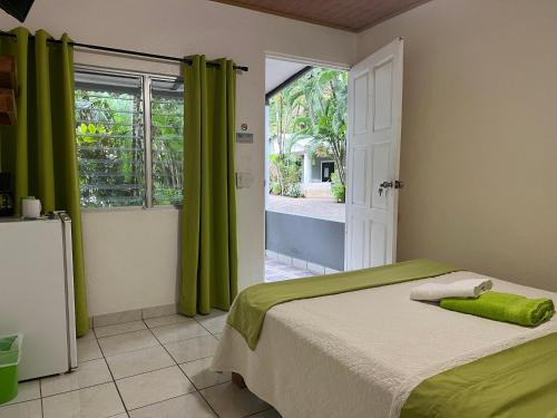 a bedroom with a bed with green curtains and a window at Villas Majolana in Herradura