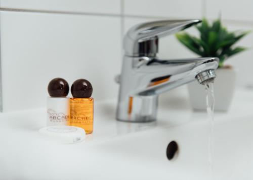 a bathroom sink with a faucet and a bottle of soap at Arcade Hotel in Wuppertal