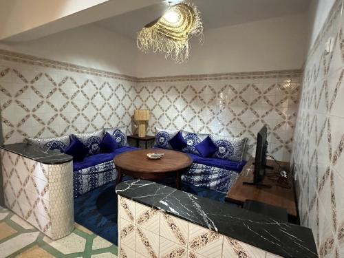 a living room with a blue couch and a table at DAR SANAE SURF in Aourir