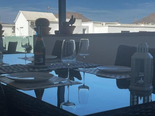 una mesa con copas y platos y una botella de vino en Apartamento San Eloy con plaza de garaje en Playa Honda
