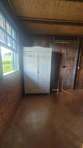 an empty room with a large white cabinet and a window at Hospedagem Pé de Serra in Botucatu