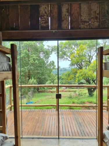 a view from the bedroom window of a wooden deck at Hospedagem Pé de Serra in Botucatu
