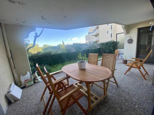 une table et des chaises en bois sur une terrasse dans l'établissement Nice Ouest- 2P au Calme, Piscine, AC, à Nice