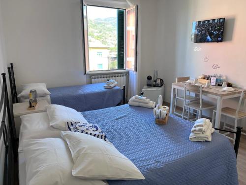 a bedroom with two beds and a table and a desk at Affittacamere Il Veliero in Levanto
