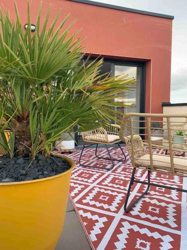 a patio with two chairs and plants in front of a building at Le Rooftop d’Isa in Colombelles