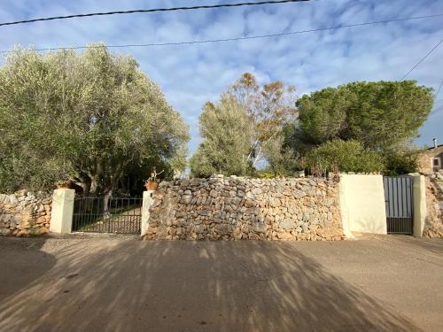 a stone fence and a stone wall with trees at Finca Casa Farah in Ses Salines