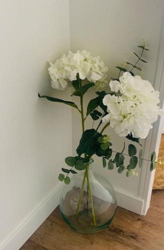a vase with white flowers in it on a table at Le Rooftop d’Isa in Colombelles