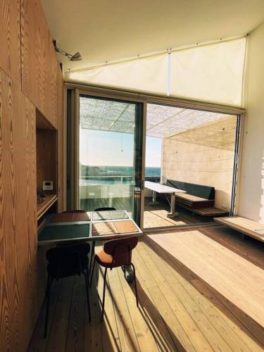 une pièce avec une table et des chaises et une grande fenêtre dans l'établissement Cabanon Le Perchoir des Goudes, à Marseille