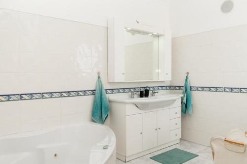 a bathroom with a sink and a tub and a toilet at Surf Yoga Ericeira Guest House in Ericeira