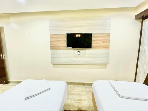 two beds in a room with a tv on the wall at Hotel Yashasvi ! Puri fully-air-conditioned-hotel near-sea-beach-&-temple with-lift-and-parking-facility breakfast-included in Puri