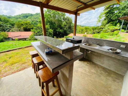 a kitchen with a counter with a sink and chairs at Tabaco Lodge #2 a solo 5 minutos de Playa Carrillo in Carrillo