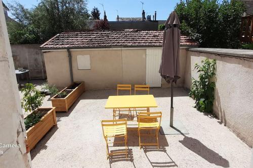 un patio avec une table, des chaises et un parasol dans l'établissement Bel appartement rez-de-chaussée cour proche centre, à Bourges
