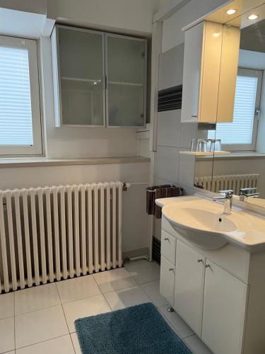 a white bathroom with a sink and a radiator at Guesthouse Nice room in Zadar