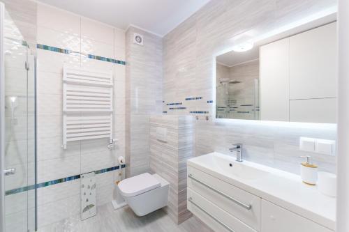 ein weißes Badezimmer mit Toilette und Waschbecken in der Unterkunft Apartament Szafir w budynku basenowym Morska Klifowa Rewal in Rewal