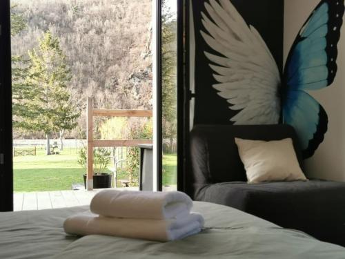 een slaapkamer met een bed met een vlinderschilderij aan de muur bij Le Ponton des Sympetrums in Aurec-sur-Loire