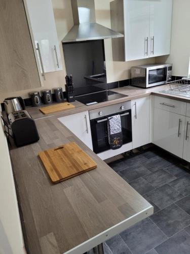 a kitchen with white cabinets and a wooden counter top at Room 3 Penrhyn drive in Llandrillo-yn-Rhôs