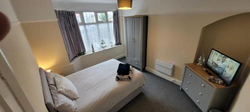 a bedroom with a bed and a dresser and window at Room 3 Penrhyn drive in Llandrillo-yn-Rhôs