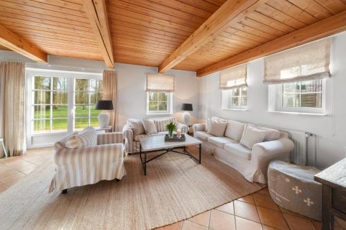 a living room with white furniture and wooden ceilings at Gut Oehe in Maasholm