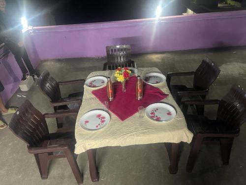 a table with plates and flowers on top of it at Hotel PNR'S Paradise in Ooty