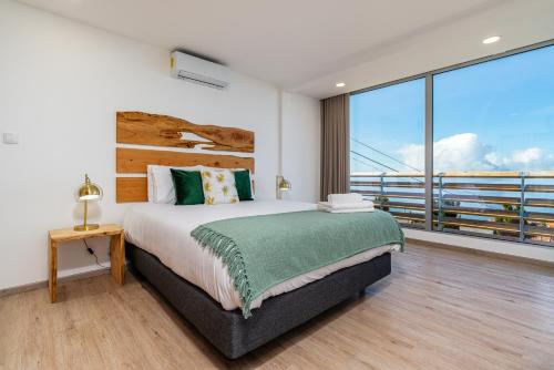 ein Schlafzimmer mit großem Bett und Balkon in der Unterkunft Bella Vista (Heated Pool & Private Parking) in Arco da Calheta