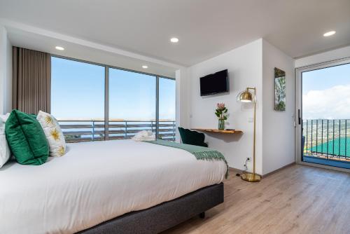 a bedroom with a large bed and large windows at Bella Vista (Heated Pool & Private Parking) in Arco da Calheta