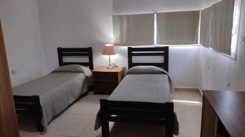 1 dormitorio con 2 camas y mesa con lámpara en Casa en Pinchas en Agua Blanca