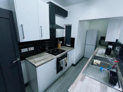 a kitchen with white cabinets and a stove and a sink at Modern 3 bedroom house in Birmingham