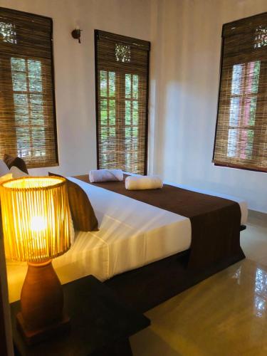 sypialnia z łóżkiem z lampką i oknami w obiekcie Nature Retreat Galle w mieście Galle