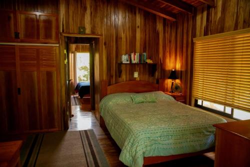 een slaapkamer met een bed in een kamer met houten wanden bij Rancho Costafalo Eco-Tourism Farm in Quebrada Grande