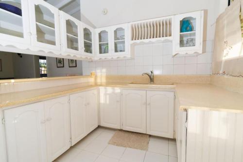 una cocina blanca con armarios blancos y fregadero en 2 Bedroom Apartment at Maynards en Saint Peter