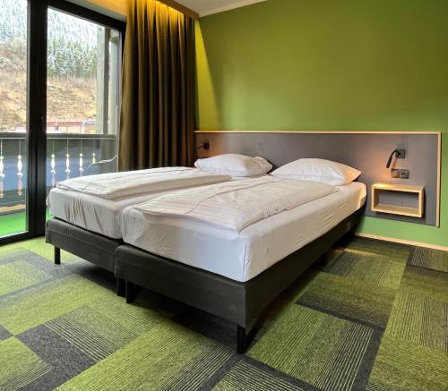 a large bed in a room with a green wall at Hotel Simader in Bad Gastein