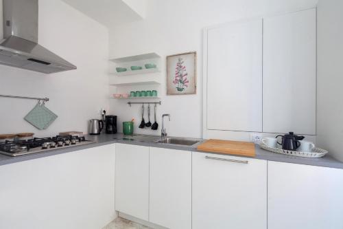 a white kitchen with white cabinets and a sink at "Vicolo Apartment" is a Two-story Apartment, 2BDR, additional Sofabed, 2,5 BTH, Aircondo, Pedestrian Centre, Private Parking 600mt far, easy to train and ferries, city life in La Spezia