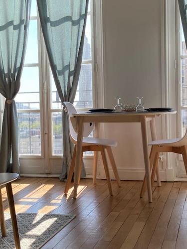 une table et des chaises dans une pièce avec une fenêtre dans l'établissement Appartement Perret vue sur mer, au Havre
