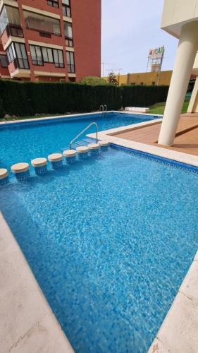 卡尔佩Atico Playa Arenal Calpe的建筑物旁边有一个带凳子的大型蓝色游泳池