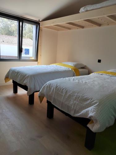 une chambre avec deux lits et une fenêtre dans l'établissement Joyau au cœur de la forêt, à La Guérinière