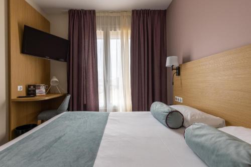 a hotel room with a bed and a television at Brit Hotel Europ Bergerac in Bergerac