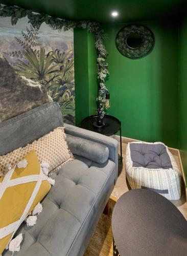 - un salon avec un canapé et un mur vert dans l'établissement Little Jungle Atypique Nevers BY Primo Conciergerie, à Nevers
