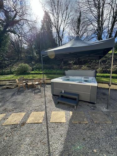 a hot tub under an umbrella on a patio at Cowslip Cottage Serenity with Jacuzzi in Saundersfoot