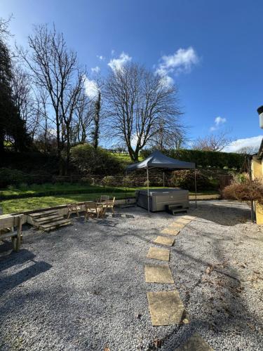 a picnic area with benches and an umbrella at Cowslip Cottage Serenity with Jacuzzi in Saundersfoot