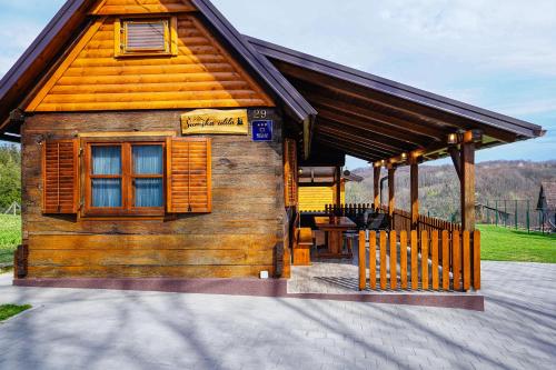 a small wooden cabin with a porch and a fence at Kuća za odmor Šumska idila in Velika Gorica