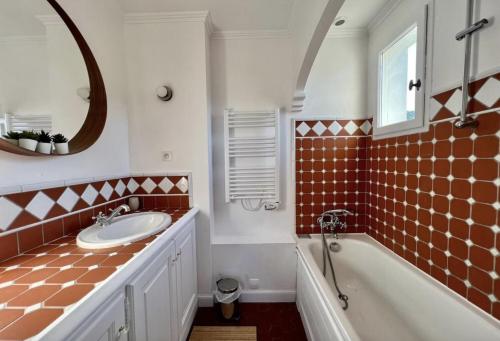 een badkamer met een wastafel, een bad en een spiegel bij One Palm in Grimaud