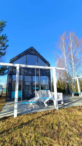 a glass house on a wooden deck with benches at Lazurowy Brzeg in Przejma Wielka