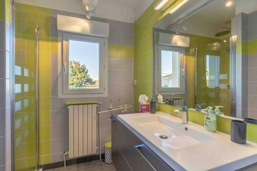 uma casa de banho com um lavatório, um espelho e um chuveiro em La Maison d’Eysines em Eysines