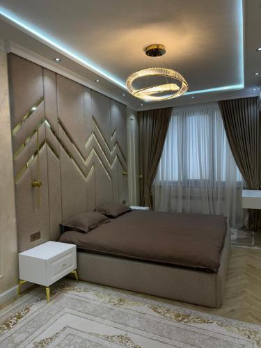 a bedroom with a large bed and a chandelier at Lux 3-roomed apartment close to the Registan Amaliapartment in Samarkand