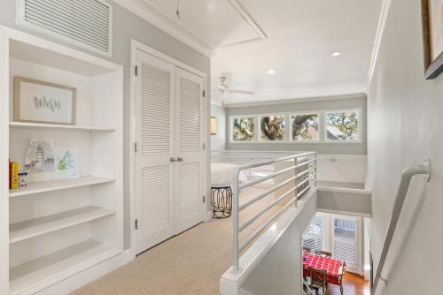 a white hallway with a staircase with white shelves at The Coral Door Beach House - 4315 Fourth Street in Saint Simons Island