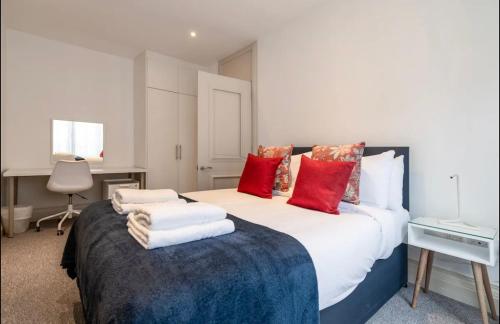una camera da letto con un grande letto con cuscini rossi e bianchi di Luxury 2 bedroom house near Mayfair - Entire Home a Londra