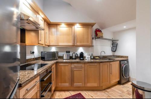 una cucina con armadi in legno, lavandino e lavastoviglie di Luxury 2 bedroom house near Mayfair - Entire Home a Londra