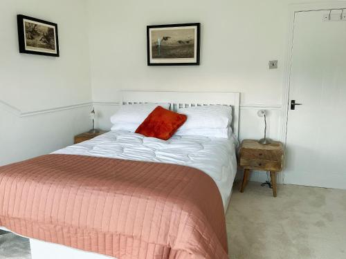 a bedroom with a bed with a red pillow on it at Poppy Cottage in Eryholme