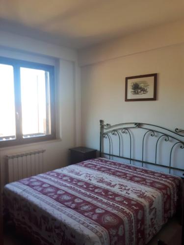a bedroom with a bed with a red blanket and a window at RESIDENCE EDELWEISS in Spogna