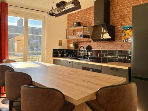 a kitchen with a wooden table and a brick wall at Légendes de la piste - SOnights in Château-du-Loir